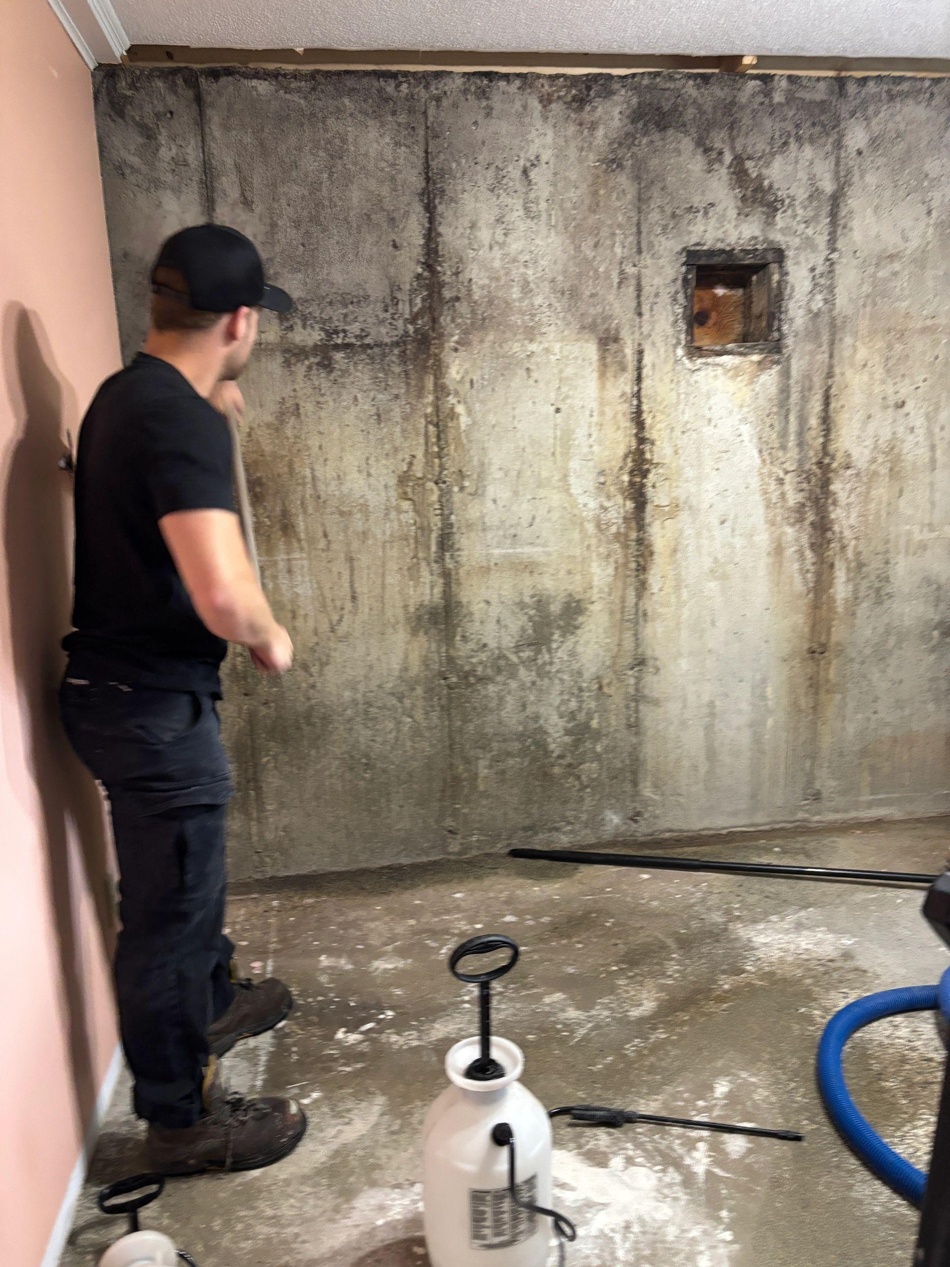Technicien en train de traiter un mur de fondation contaminé dans un sous-sol